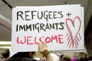 Person holding a sign that says Refugees and Immigrants Welcome