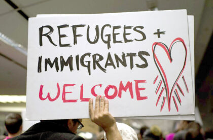 Person holding a sign that says Refugees and Immigrants Welcome